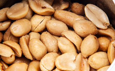 Obraz premium Macro shot of a scattering of roasted peanut halves with salt. The dense texture of these popular nuts, the concept of a healthy snack, protein, and natural food.