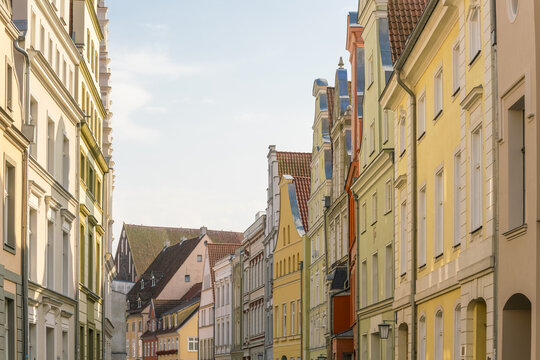 View of vibrant, colorful buildings with stepped gables line the street in a historic old town, their pastel hues against the clear sky, Stralsund, Mecklenburg-Vorpommern, Germany.