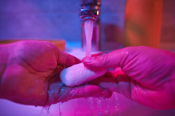 Human hands are turning the home faucet on and washing it with soap and clean tap water for good...
