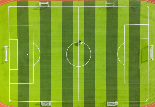 Aerial view of a meticulously striped green and white football field, bisected by crisp white lines, promising games under a bright sky, Changsha, Hunan, China.