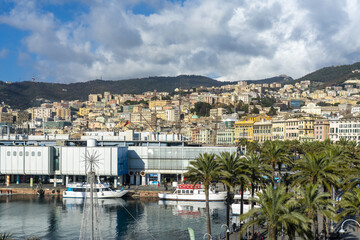 Genoa, Italy - 27 December 2022: View of the bustling harbor, where modern architecture meets the vibrant colors of the city nestled against the backdrop of rolling hills.