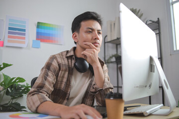 Young Male Graphic Designer Looking Intently at His Computer Screen With Hand on His Chin