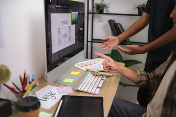Two Graphic Designers Collaborating on Monitor