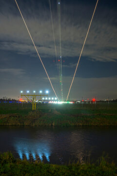 Plane landing at Rotterdam airport at night with light trails and reflections
