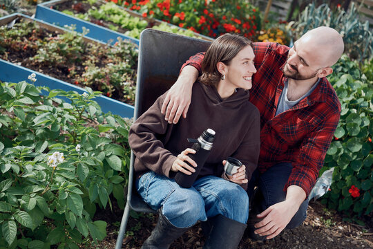Couple sitting in a wheelbarrow with coffee flask at London allotment