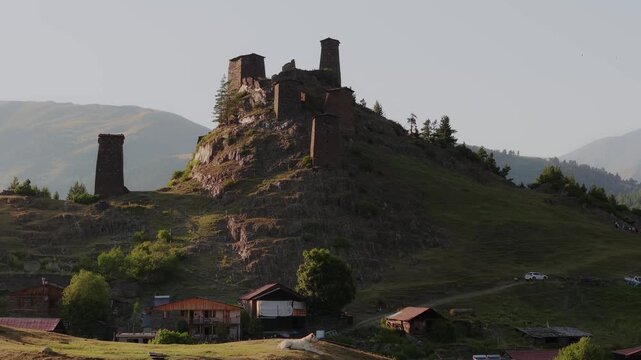Aerial view of ancient stone towers perched on a rocky hill, bathed in the warm light of the Caucasus mountains, Omalo, Kakheti, Georgia.