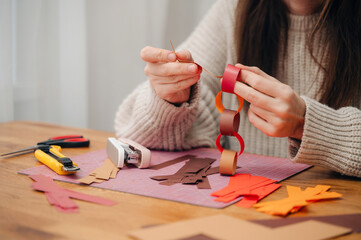 Girl making a paper garland at a table, enjoying creative holiday crafting.