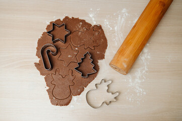 Cookie dough with cut-out shapes and metal cutters on a table, festive baking process.