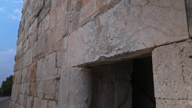 Upward pan along weathered stone blocks of an ancient fortress wall in Zippori National Park, Israel. Archaeological heritage, textured masonry, blue sky, travel history and culture 
