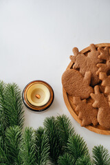 New Year still life with candle, cookies, and fir branches on a table.