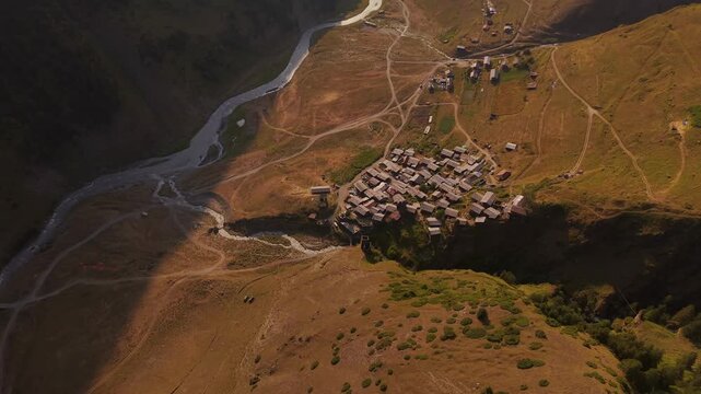 Aerial view of Dartlo and Kvavlo, a village nestled in the rugged Caucas mountains, exhibiting a tapestry of dwellings and a winding river, Dartlo, Tusheti, Georgia.
