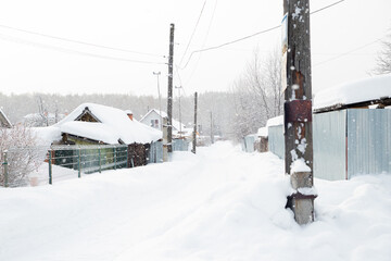 Snowy rural street with village house roofs covered in deep snow during a winter blizzard. Idyllic landscape showcasing a white winter wonderland. blizzard