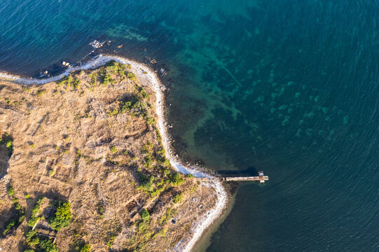 Aerial view of the rugged coastline where golden grass meets the deep blue sea, creating a stunning contrast of colors and textures, Nos Chervenka, Chernomorets, Bulgaria.