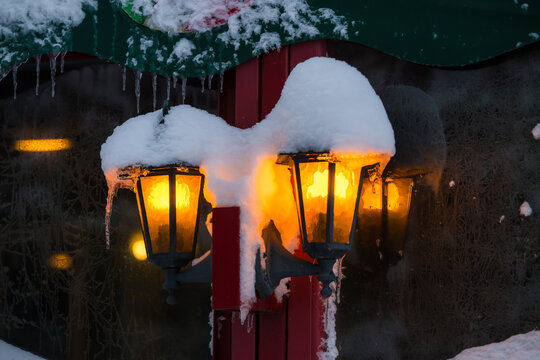 View of snow-laden lampposts casting a warm glow against a cold, wintery backdrop, icicles hanging like frozen tears in Parnu, Estonia.