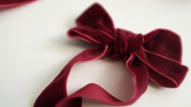 Red velvet ribbon bow tie. Christmas present decoration. Aesthetic traditional Christmas or winter holidays. Elegant holiday gift wrap or home decoration.