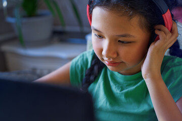 Child with headphones learning online at home using laptop