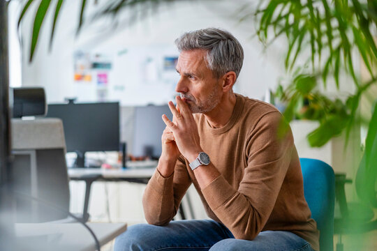 Contemplative man with hand on chin sitting at office