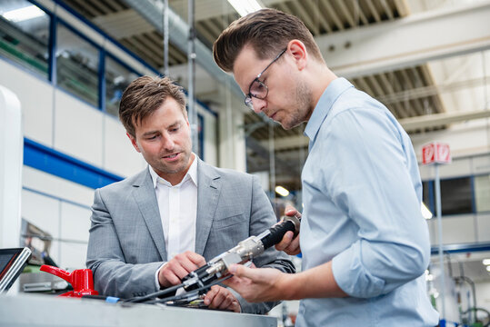 Business engineers discussing machinery in production hall
