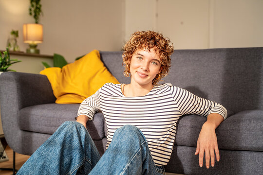 Curly haired woman in striped shirt relaxing in cozy living room