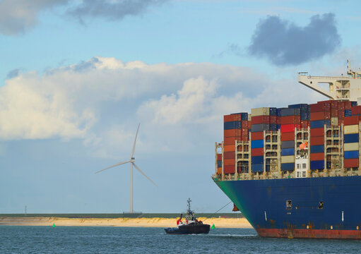 LNG powered container ship entering Rotterdam harbour with wind turbine