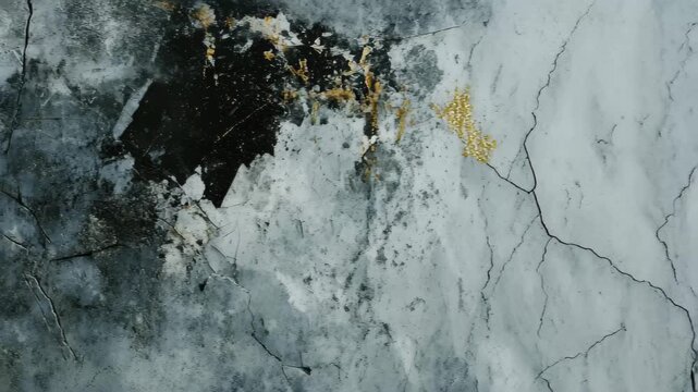 A close-up view of a weathered gray wall featuring cracks and patches of peeling paint. The surface reflects urban decay, creating a raw, industrial aesthetic suitable for various design themes.