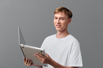 Young man with tablet and laptop in a studio, showcasing technology and learning for education, training, digital workflow, collaboration, and tasks for professional use.