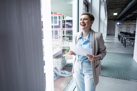 Smiling businesswoman holding documents in modern coworking office