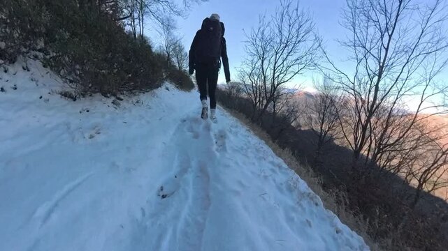 Monte Lema, Varese, Italy: Hiking day in the mountains on the snow, girl walking halfway up the hill