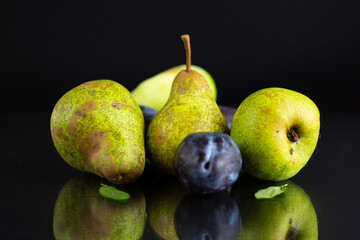 Ripe pears and plums on a black background © Peredniankina