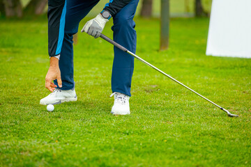Golfer's hand placing ball on a golf tee