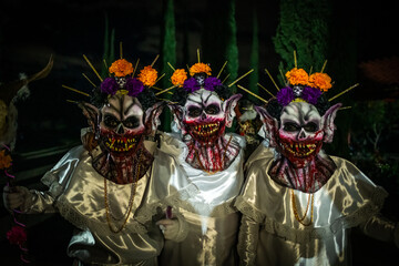Santa Maria del Tule, Mexico - 03 November 2023: View of haunting figures adorned in white, their grotesque masks a chilling spectacle against the solemn backdrop of Day of the Death cemetery.