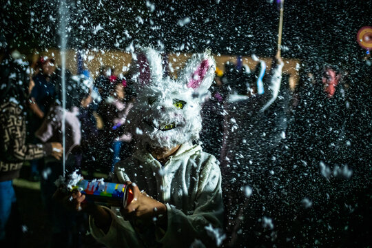 Santa Maria del Tule, Mexico - 03 November 2023: View of a surreal scene at Day of the Death cementary with a person in a rabbit mask amid a blizzard of soap suds.
