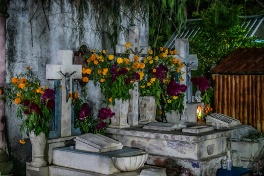 Santa Maria del Tule, Mexico - 03 November 2023: View of the Day of the Dead cementary, with vibrant flowers adorning the aged graves under a dim light.