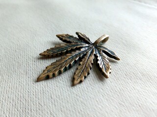 Hemp metal pendant lying in perspective on white jeans background
