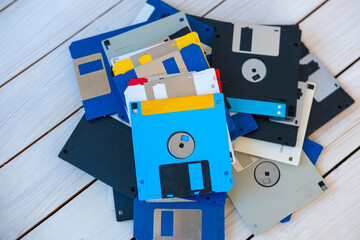 Colorful pile vintage 3.5 inch floppy disks on wooden surface, retro computing, obsolete data storage, tech nostalgia, digital history, collection old media formats 80s, 90s, nostalgic tech memory