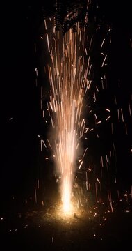 Focus shift shot of a ground flower pot cracker bursting with bright sparks on a dark background, perfect for Diwali, New Year, festive celebrations, and cinematic overlays.