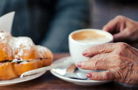 An elderly couple drinking morning coffee with croissants.