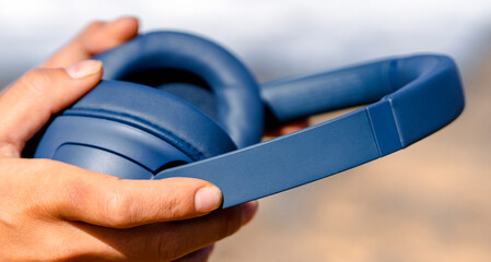 A girl holds a wireless headphones in hands, closeup view.