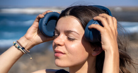 A girl with a wireless headphones, is listening music outdoors.