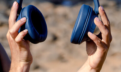 A girl holds a wireless headphones in hands, closeup view.