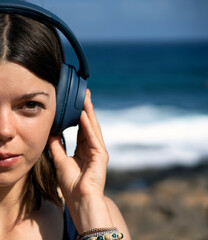 A girl with a wireless headphones, is listening music outdoors.