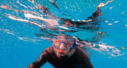 Man is diving, snorkeling with a mask and snorkel in the ocean.