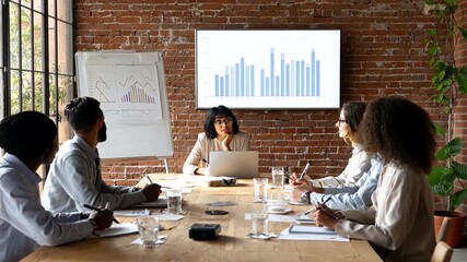 Diverse business team in a meeting analyzing financial data on a screen. - Powered by Adobe