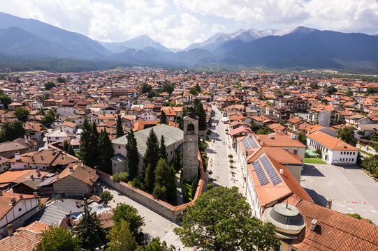Aerial view of terracotta rooftops cascade across the urban tapestry, nestled beneath the Pirin Mountains, with the Holy Trinity Church standing tall, Bansko, Blagoevgrad Province, Bulgaria.