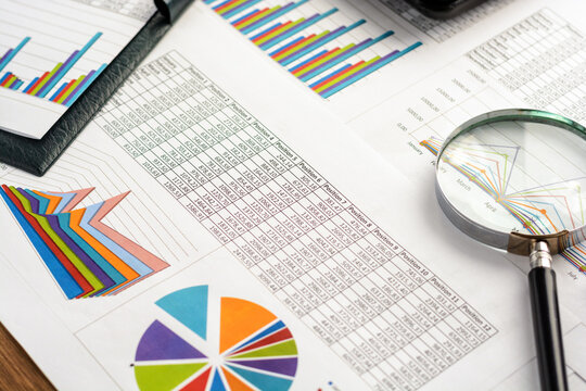 financial analysis charts and graphs with magnifying glass and tablet on desk - Powered by Adobe