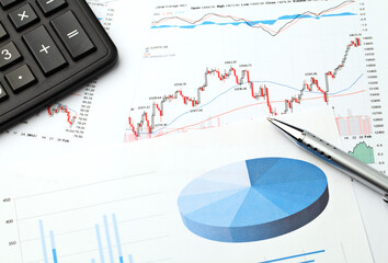 financial charts and graphs with calculator and pen on desk