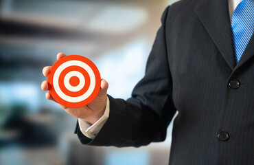A businessman holds a target in his hand. Goal setting and business management. Strategic focus, clear objectives, leadership vision. Performance measurement and success planning.