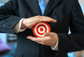 A man in a business suit holds a target in his palms. A candidate for a position. Setting a goal to achieve. Career aspiration, recruitment decision. Evaluation process and personal responsibility.