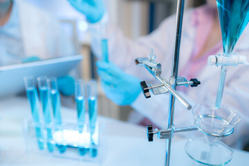 Two chemists in white lab coats working together in a modern laboratory surrounded by scientific equipment, computers, and glassware, representing teamwork in scientific research.