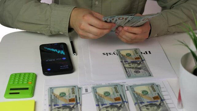 This detailed scene shows an investor cross-referencing IPO data on paper and phone while physically organizing cash into stacks. It represents deep due diligence.